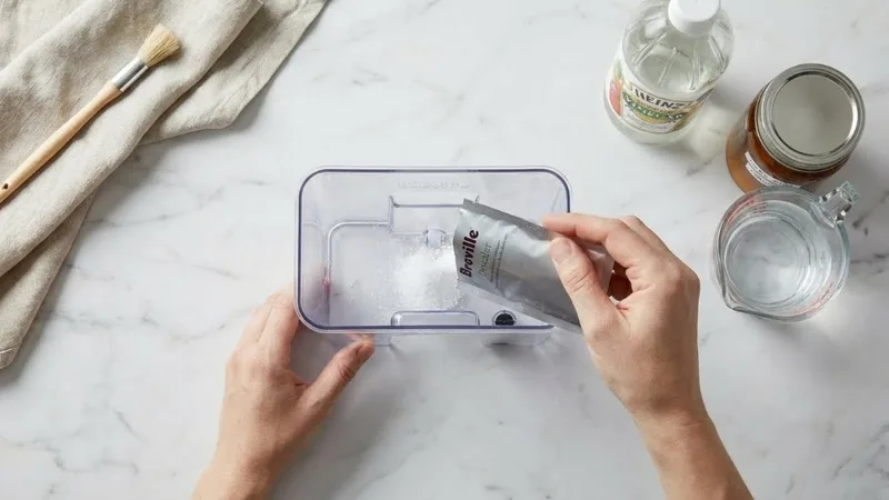 Hands pouring descaling solution into Breville water tank