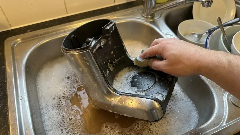 Breville bean hopper being washed with soapy water in a kitchen sink