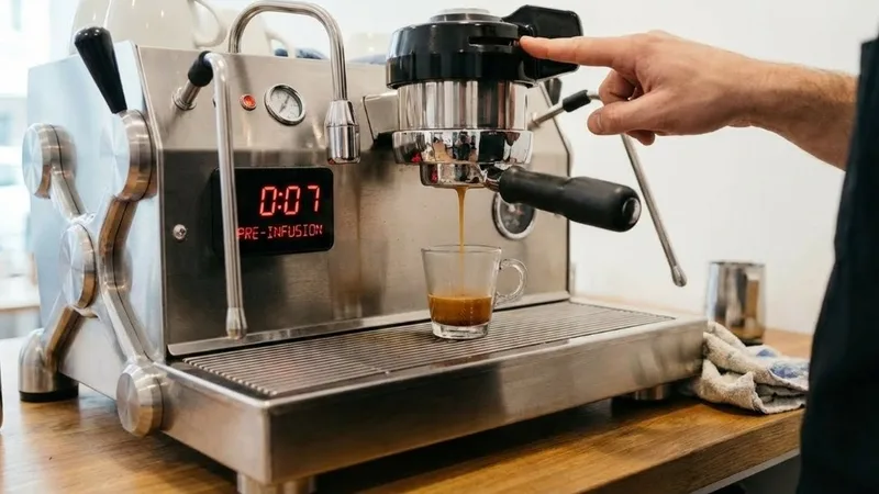 Barista holding the brew button to manually control the pre-infusion duration on an espresso machine